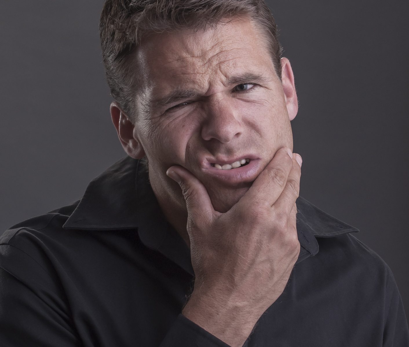 A man holding his jaw due to a toothache or tooth trauma